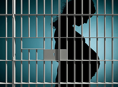 An illustration shows a silhouette of a pregnant woman in a jail cell 